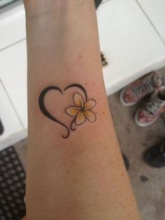 a woman's arm with a small heart and flower tattoo on the left wrist