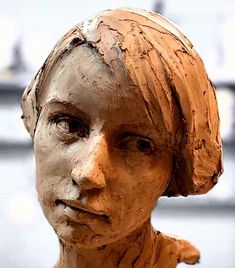 a close up of a wooden statue of a woman's head with hair pulled back