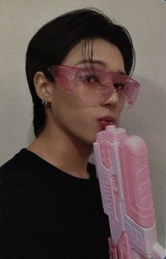 a woman wearing glasses and holding a pink plastic object in front of her face,