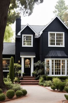 a black house with white trim and lots of windows on the front door is surrounded by greenery