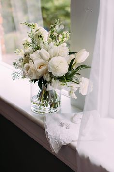 a vase filled with white flowers on top of a window sill