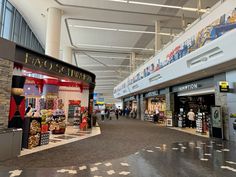 the inside of an airport with people walking around and shops lined up on either side