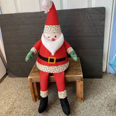 a stuffed santa clause sitting on top of a wooden bench in front of a door