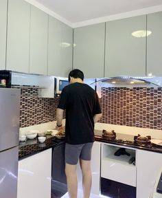 a man is standing in the kitchen preparing food on the stove top and countertop