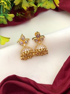 These American Diamond Small Gold Jhumka Earrings with Ruby Emerald CZ color stones are perfect for daily wear. Crafted with 22k gold tone, these earrings feature ruby and emerald stones fashioned in a classic small jhumka design. Ideal for an elegant look, these Indian earrings are sure to become an instant favorite. 22k Gold Hand Set Jhumkas As Gift, Gift 22k Gold Hand Set Jhumkas, Gold Plated Cutdana Jhumkas As Gift, Diwali Anniversary Jhumkas With Latkans, Gold Bollywood Earrings With American Diamond, Gold Kundan Jhumkas For Anniversary, Diwali American Diamond Earrings With Latkans, Festive Bollywood Jhumkas For Anniversary, Bollywood Style Festive Jhumkas For Anniversary