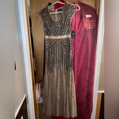 two dresses hanging on a closet door next to a pink velvet coat hanger in the doorway