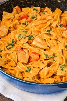 a skillet filled with pasta and chicken on top of a table