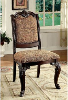 an ornate wooden dining chair with upholstered back and seat cushion, in front of a window