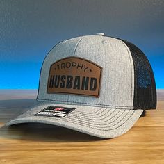 TROPHY HUSBAND Funny Leather Patch Hat. Specifications: 🧢 Richardson original 112 trucker; adjustable for the perfect fit 🎩 60/40 cotton/polyester blend for comfort 📏 One size fits most 🏷️ Expertly laser engraved leatherette patch design 📦 Ships in 2 to 3 business days from our Orlando Studio Care Instructions: 🚫 Do not wash; spot clean only Please Note: 🌈 Colors may vary from photos based on your viewing screen. Funny Hat Ideas, Leather Patch Hat Ideas, Orlando Studios, Trophy Husband, Husband Funny, Hat Bar, Leather Patch Hat, Cowboy Stuff, Patriotic Hats