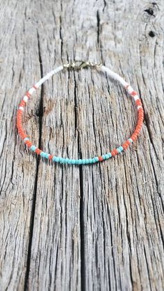 an orange and turquoise beaded bracelet on wooden planks