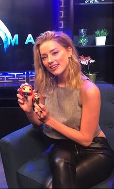 a woman sitting on top of a chair holding a small toy in her right hand