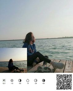 two people are sitting on a dock by the water and one person is looking at something