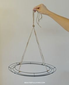 a hand is holding a wire hanging from a circular object with two strings attached to it