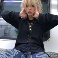 a woman sitting on top of a metal bench next to a train window with her hands behind her head