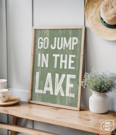 a sign that says go jump in the lake next to a cup and saucer