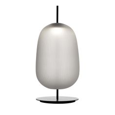 a white lamp sitting on top of a black stand next to a white wall and floor