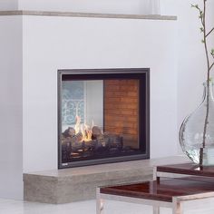 a fire place in a living room next to a table and vase with flowers on it