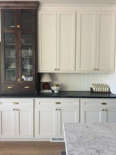 a kitchen with white cabinets and marble counter tops