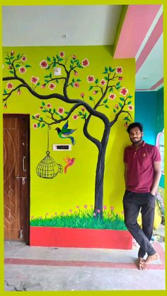 a man standing in front of a tree painted on the wall