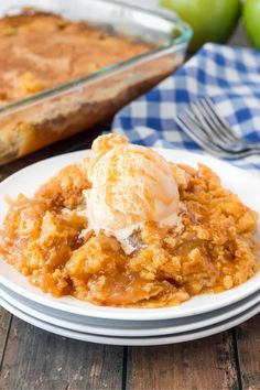 a white plate topped with an apple cobbler next to a casserole dish