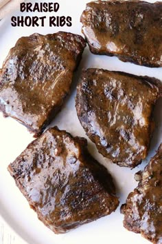 some steaks are on a white plate with the words, braised short ribs