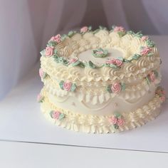 a three layer cake with white frosting and pink flowers on it's sides