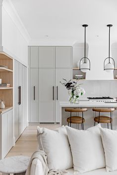 a living room filled with furniture and lots of white decor on top of a hard wood floor