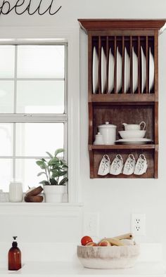 a wooden shelf filled with dishes next to a window