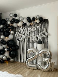 balloons and streamers are on the floor in front of a black and white backdrop