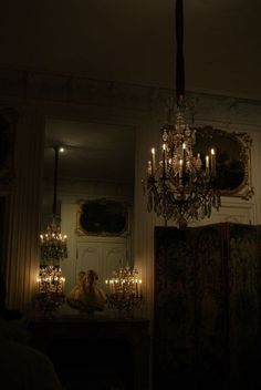 a chandelier hanging from the ceiling in a dark room with candles on it