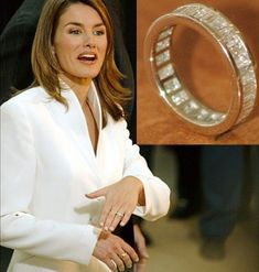 a woman wearing a white suit and diamond ring in front of a photo with people standing around