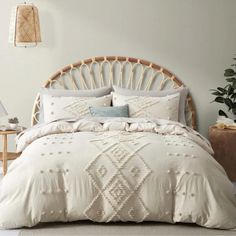 a bed with white sheets and pillows in a room next to a potted plant