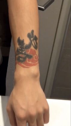 a person with a mickey mouse tattoo on their arm holding onto a white counter top