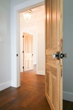 an open door in a white room with wood floors and hard wood flooring on the walls