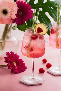 two glasses filled with raspberry lemonade next to pink flowers and greenery