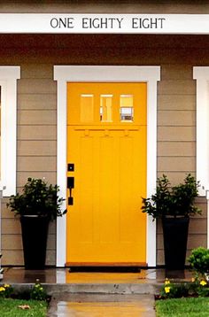 a yellow front door with two planters on each side and the words one eighty eight above it