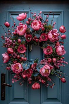 a blue door with a pink wreath and flowers hanging on it's front door