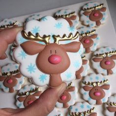 a hand is holding a cookie decorated like a reindeer