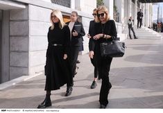 two women walking down the street in black outfits