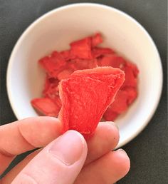 someone holding up a piece of watermelon in front of a white bowl with the words how to make watermelon chips in 10 minutes