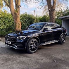 a black car parked in front of some trees