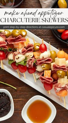 an appetizer with olives, ham and cheese on skewers next to dipping sauce