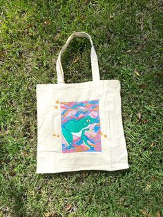 a tote bag sitting in the grass on top of some green grass with an image of a whale