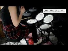 a woman sitting in front of a drum set