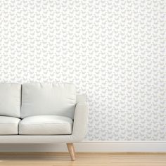 a white couch sitting in front of a wallpapered with grey birds on it