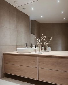 a bathroom with two sinks and a large mirror above the sink is lit by recessed lights