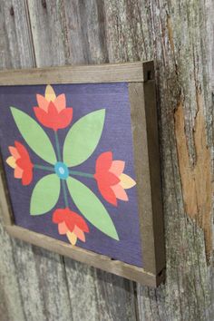 a painting is hanging on the side of a wooden fence with flowers painted on it