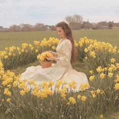 a woman sitting in the middle of a field with yellow flowers