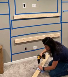 a woman is working on some wood planks in a room that has been painted gray and blue