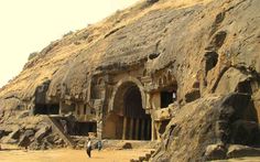 some people are standing in front of an old rock structure with carved doorways and steps